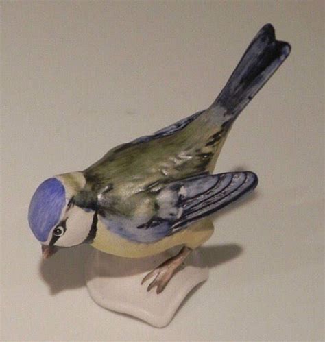 A Small Figurine Of A Bird Sitting On Top Of A White Tablecloth