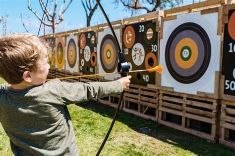 Crian A Brincando Um Arco E Flechas Jogando Os Contra Um Alvo