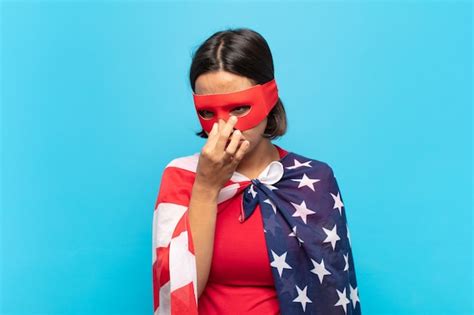 Mujer latina joven que se siente disgustada tapándose la nariz para