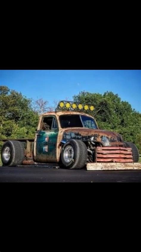 An Old Truck Is Parked On The Side Of The Road With Trees In The Background