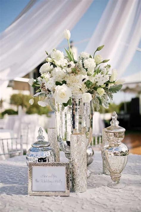 A Table Topped With Vases Filled With White Flowers