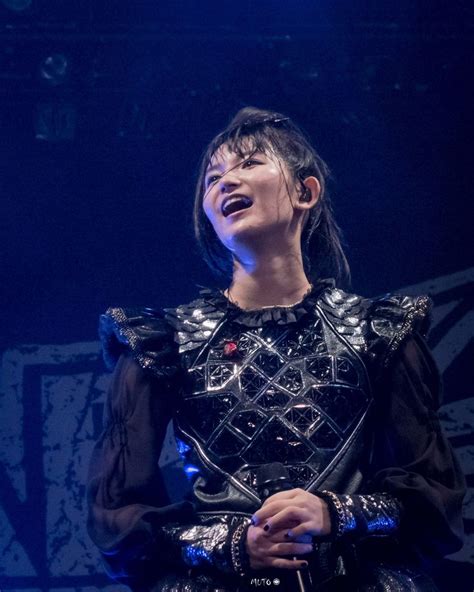 A Woman In Black Dress Standing On Stage With Her Eyes Closed And Mouth