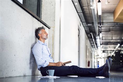 Mature Businessman Sitting On The Floor Leaning Against The Wall Stock