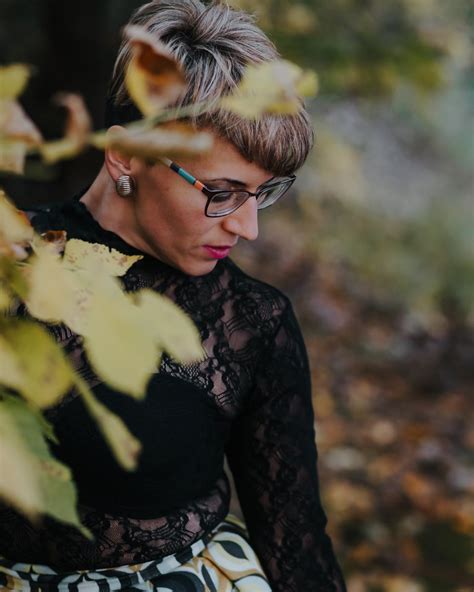Gratis billede: Blond kvinde med briller holder blomster i højt græs