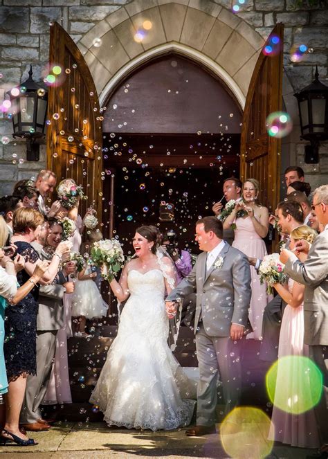 A Bride And Groom Are Surrounded By Bubbles As They Walk Down The Aisle