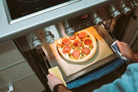 Vista Elevada De Las Manos De Los Hombres Sacando Del Horno Una Pizza