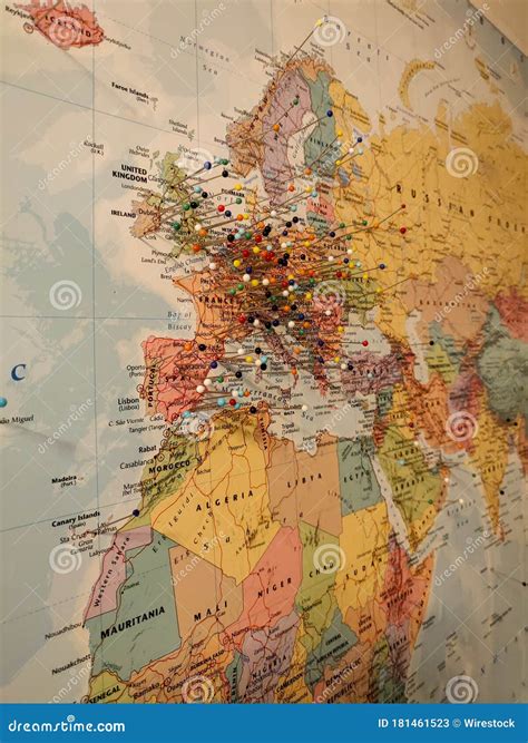 Vertical Shot Of A World Map On A Wall With Colorful Pins Attached On