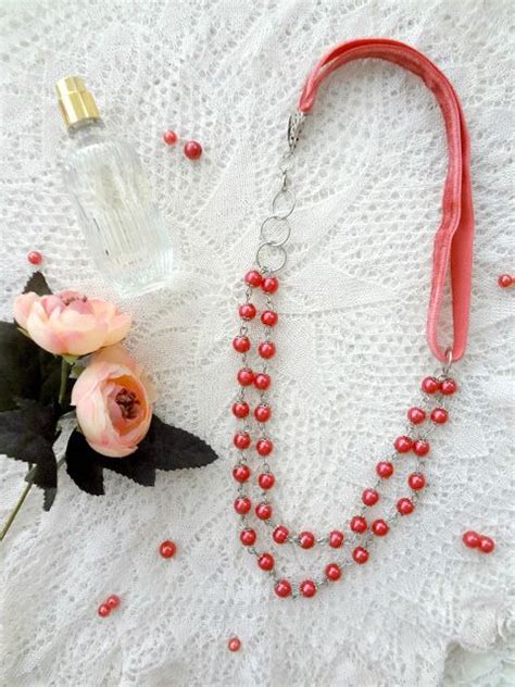 A Necklace With Beads And Flowers On A White Tablecloth Next To A