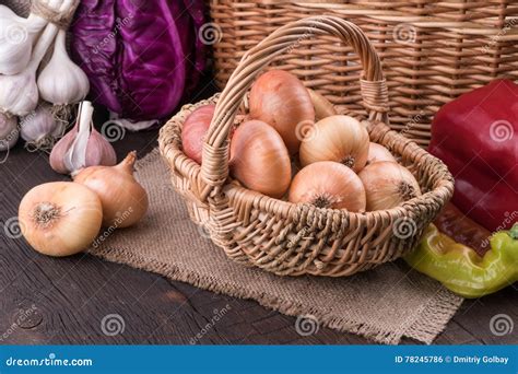 Cebolas Em Uma Cesta De Vime Na Tabela De Madeira Velha Foto De Stock