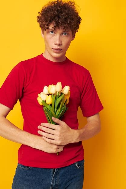 Chico con pelo rizado rojo posando románticamente con un ramo amarillo