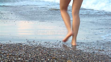 Tanned Female Legs On Beach Water Splashing On Feet In Ocean On Sandy