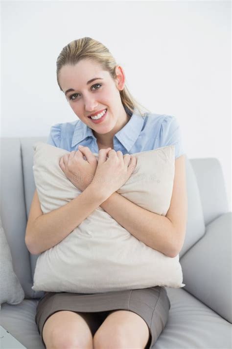 Cute Chic Businesswoman Holding A Pillow Sitting On Couch Stock Photo