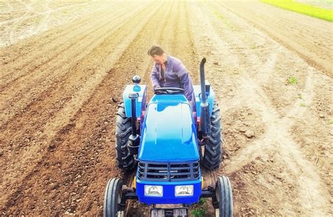 Premium Photo | A farmer on a tractor cultivates a farm field.