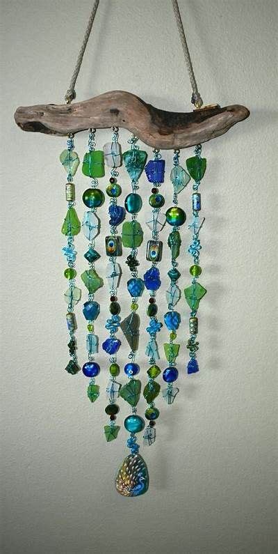 A Piece Of Driftwood Hanging On The Wall With Glass Beads And Seashells