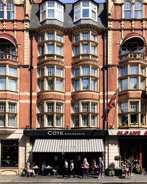 people are walking in front of a tall building with many windows and awnings