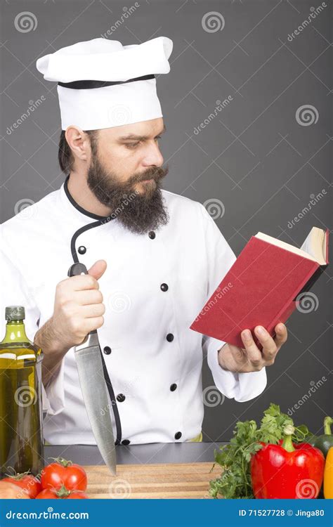 Young Chef In Uniform Reading A Recipe Ready To Cook Stock Photo