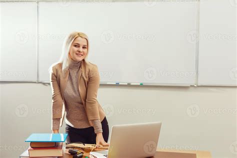 Pretty Teacher Smiling At Camera At Back Of Classroom At The Elementary School 15570790 Stock