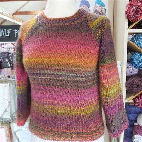 A Colorful Sweater Is Displayed On A Mannequin In Front Of Some