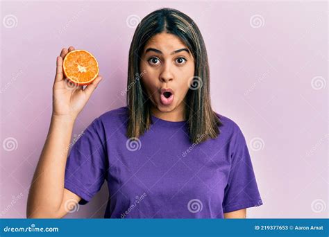 Jovem Latina Segurando Fatia De Laranja Fresca Assustada E Surpreendida Boca Aberta Para