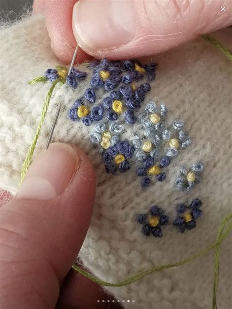 Someone Is Stitching Flowers On The Side Of A White Knitted Object With