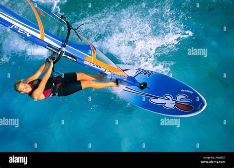 Aerial Shot Of Smiling Female Windsurfer Looking At Viewer Sailing On