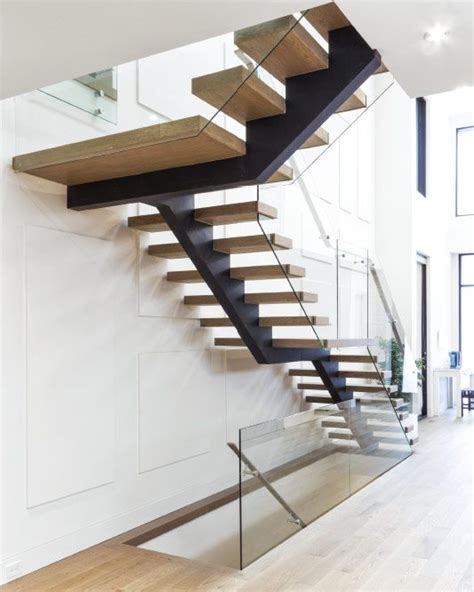 A Modern Staircase With Glass Railing And Wooden Handrail