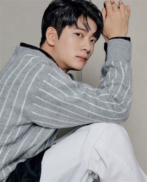 a young man sitting on top of a chair wearing white pants and a gray ...