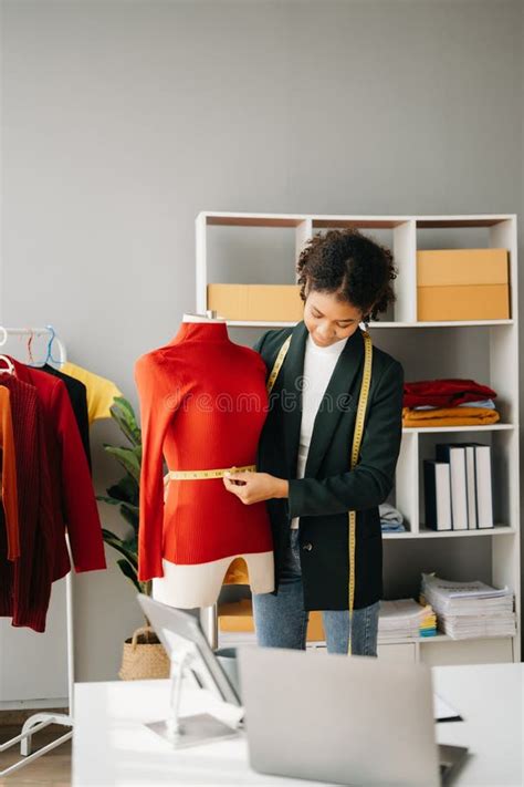 Calm Curly Brunette Dark Skinned Woman On Desk In Office Of Fashion Designer And Holds Tablet