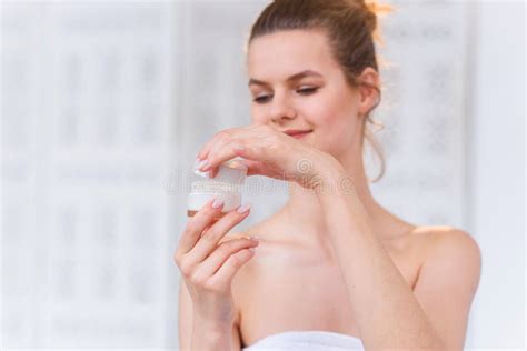 Attractive Brunette Woman Opening Jar With Cream And Smiling To The Camera In The White Stylish