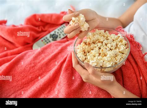 Young Woman Eating Popcorn While Watching Tv In Bedroom Closeup Stock