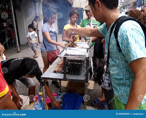 A Street Food Vendor Sells Barbecue In A Food Cart Along A Street In