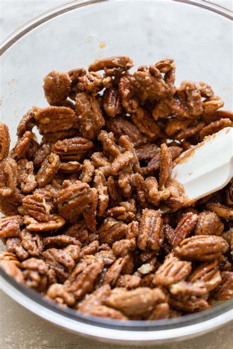 A Glass Bowl Filled With Pecan Halves Coated In The Cinnamon Sugar