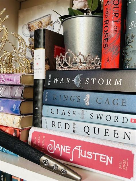 A Stack Of Books Sitting On Top Of A White Book Shelf Next To A Pen