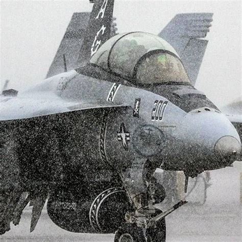 A Fighter Jet Sitting On Top Of An Airport Tarmac In The Snow With It S