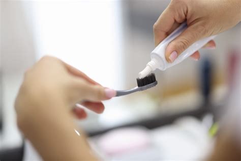 Mano Femenina Apretando La Pasta De Dientes Del Tubo En El Cepillo De Dientes Cerrar Foto Premium