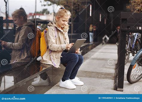 After School A Smiling And Cute Girl Sits On A Step Near A Glass