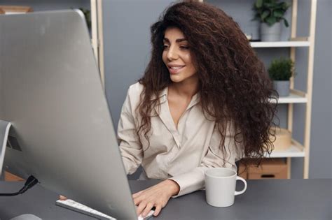 Disfruté el trabajo feliz bronceado adorable empresaria latina rizada en camisa de lino mira el