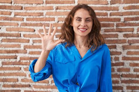 Beautiful Brunette Woman Standing Over Bricks Wall Showing And Pointing Up With Fingers Number