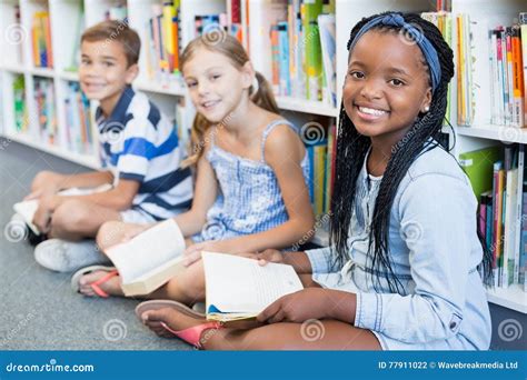 Portrait of School Kids Sitting on Floor and Reading Book in Library Stock Photo - Image of ...