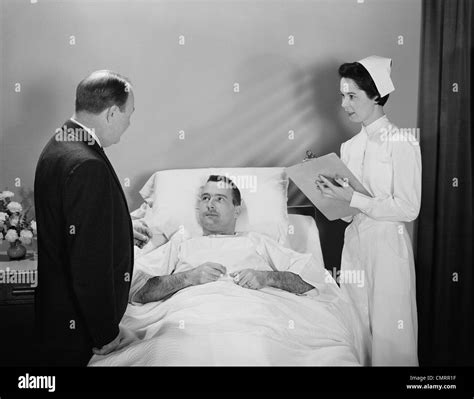 1950s Man Doctor Woman Nurse Talking With Male Patient Lying In