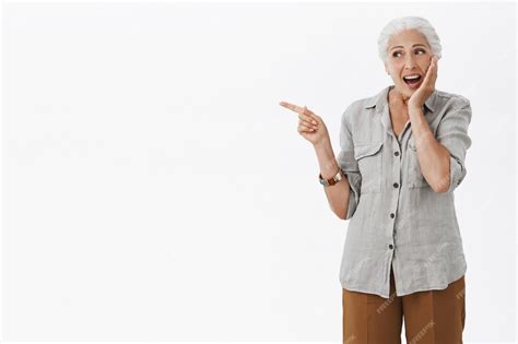 Excité Heureux Mamie Pointant Le Doigt à Gauche Et Souriant étonné Photo Gratuite