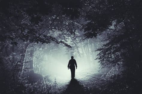 Silhouette Of Man In Dark Haunted Scary Forest On Halloween Night Stock