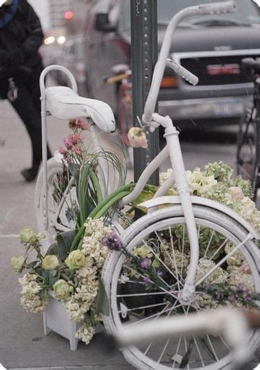 A White Bicycle Parked On The Side Of A Street Next To A Pole With