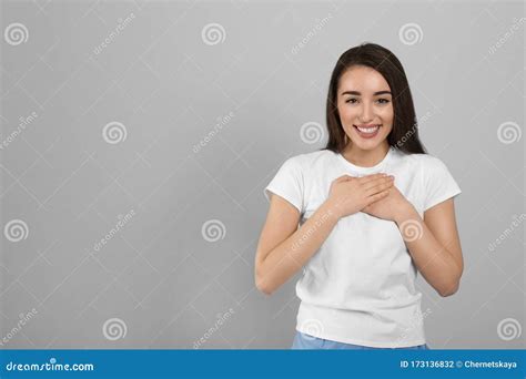 Beautiful Grateful Woman With Hands On Chest Against Grey Background