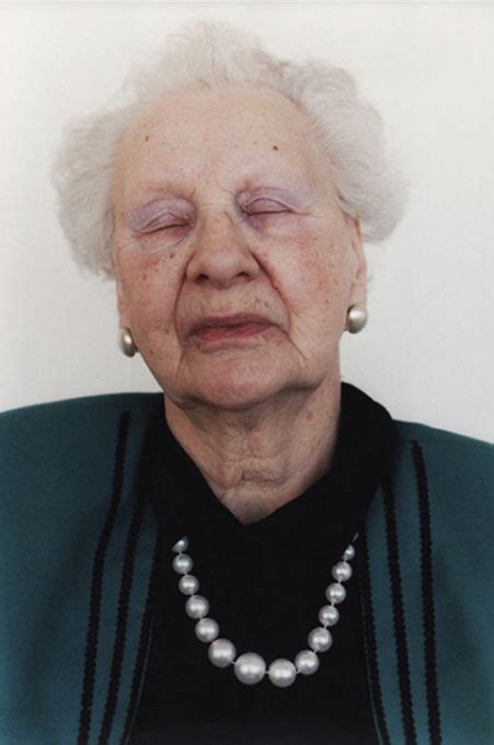 An Older Woman With White Hair And Pearls On Her Necklace Is Looking At