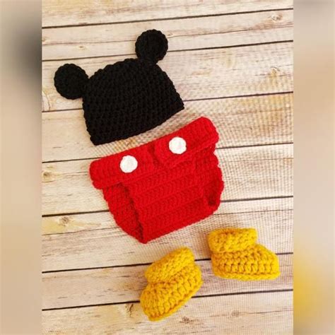 A Crocheted Mickey Mouse Hat And Booties Are Laying On A Wooden Floor