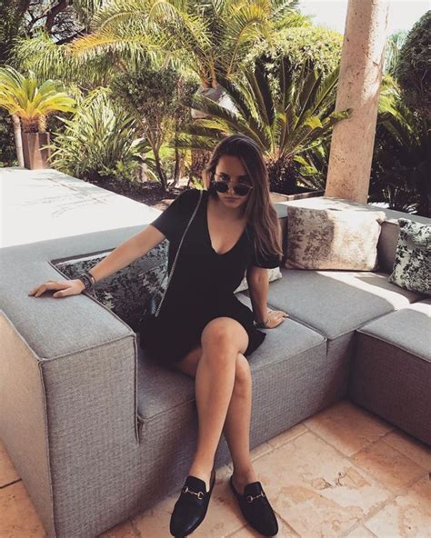 A Woman Sitting On Top Of A Gray Couch Next To Palm Trees And Water In