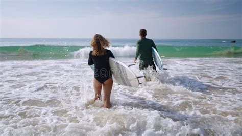 Travelling Caucasian Couple With Surfboards Running On Sandy Shore Into Ocean Water Man Woman