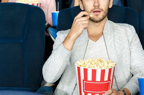 Premium Photo | Best snack for cinema. cropped shot of a man eating ...