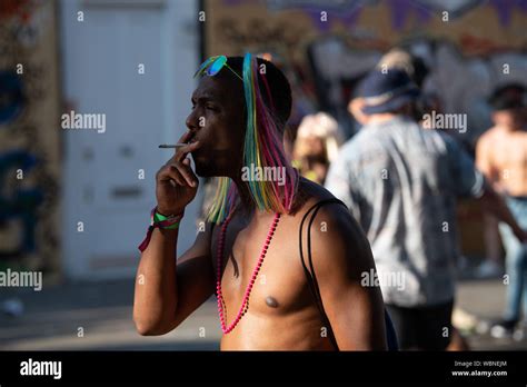 A Black Man Smoking At The Notting Hill Carnival Wearing A Pink